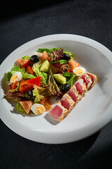 Close-up of Niçoise salad with medium seared tuna on a white plate