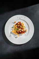 Top-view of beef medallions with vegetable puree, showcased against a textured black background