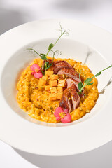 Elegant duck breast with pumpkin risotto in a shadowy white ambiance, perfect for sophisticated culinary presentations