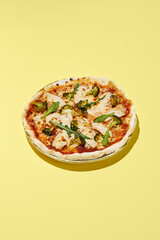 Healthy gluten-free pizza with turkey and broccoli on a bright yellow background