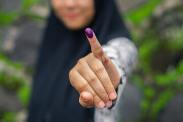 Blurry half face muslim girl showing pinky finger after voting on Indonesia presidential election....