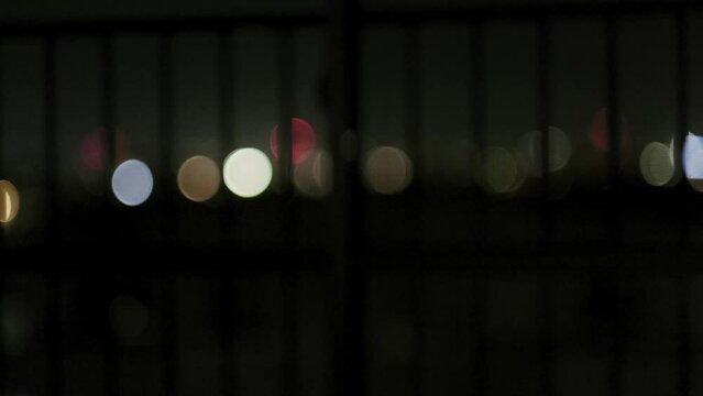 玉ボケの夜景を見た後にカーテンを閉める女性の後ろ姿