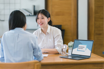 Two professional women in a casual discussing business report at office.