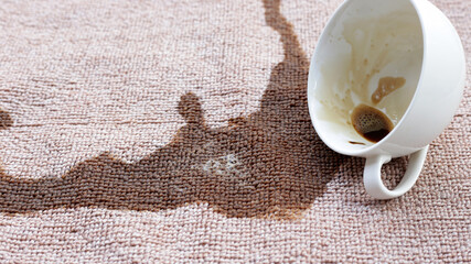Coffee spilled from white cup on the carpet