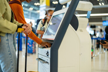 Woman friends using self Check-in kiosk machine getting airline ticket boarding pass in airport terminal. People travel with using technology on holiday vacation and airplane transportation concept.
