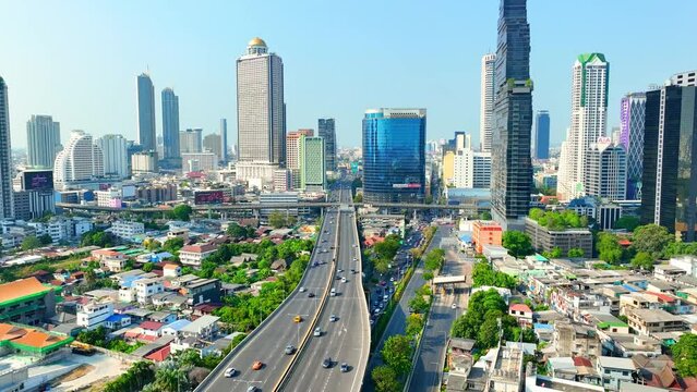 4K - Bangkok Thailand: Drone Aerial view, Over the urban sprawl, the drone hovers, a silent sentinel above towering skyscrapers and high rises, witnessing the heartbeat of the metropolis. 
