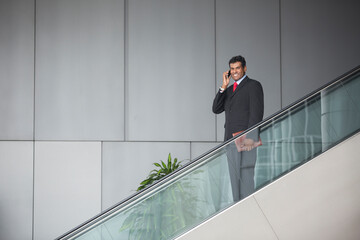 Indian businessman standing on an escalator.