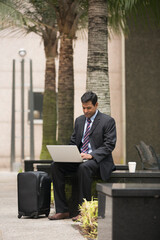 Indian businessman using his laptop outdoors.