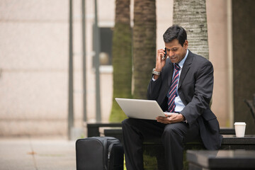 Indian businessman using his laptop outdoors.
