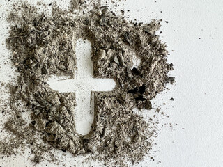 Ash Wednesday cross in pile of ashes, a symbol of dying and returning to the dust during holy day of prayer and fasting preceded by Shrove Tuesday making it Lent’s first day 46 days before Easter