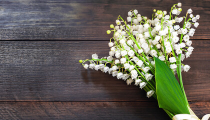 Beautiful Spring nature Background with Lily of the valley flowers. Bouquet of Lily of the valley flowers on dark wooden background. Flat lay, top view. Wide Angle Template Web banner With Copy Space