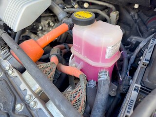 Reservoir coolant bottle in car engine compartment made of durable translucent plastic.