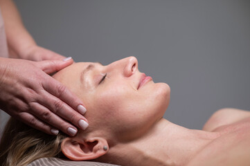 Fototapeta na wymiar Caucasian woman undergoing head and face massage procedure. 