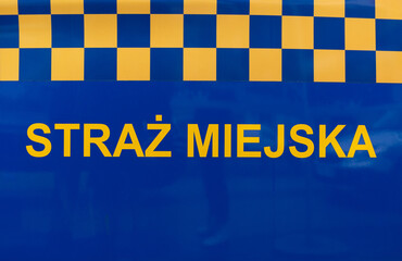 Municipal Police sign on the side door of a car. Letters in Polish language, Straż Miejska means Municipal Police. City or town officers patrol vehicle. © Longfin Media