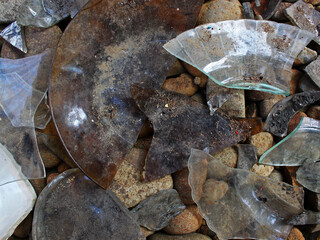 Top view of broken plates and bowls on pebbles. 