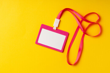 Blank nametag on a string on yellow background copy space