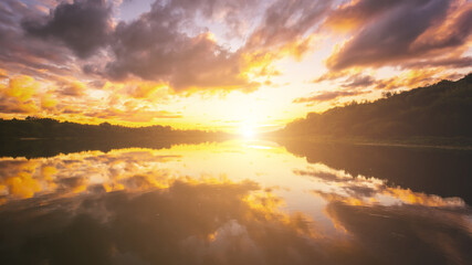 Sunrise or sunset on a lake or river with dramatic cloudy sky reflection in the water in spring....