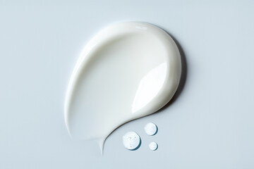 cosmetic smears of creamy texture drops of tonic serum on gray background