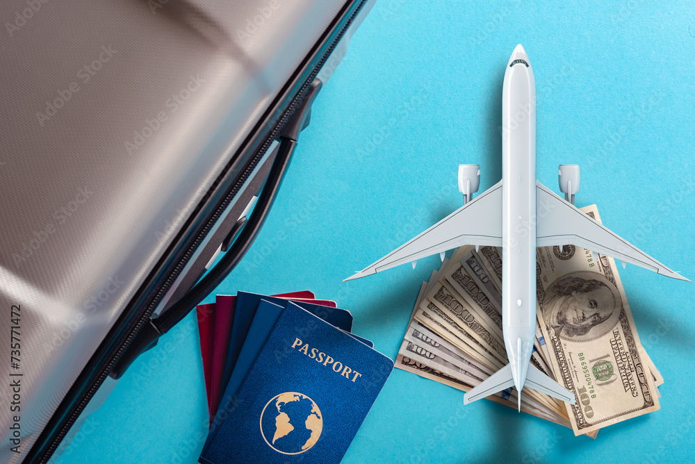 Wall mural close up of traveling passport, cash money and suitcase on blue background