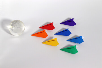 A globe and rainbow colored paper plane on a white background. The concept of social diversity.
