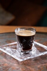 Glass cup of coffee on crystal plate, restaurant menu, dark background
