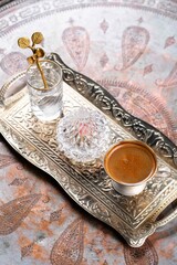 Still life with a cup of Turkish coffee and small glass of water on silver tray, rahat lukum in crystal bowl