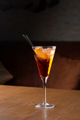A glass of cold whiskey or lemonade or fruit cocktail with straws in restaurant, dark background, relaxed evening drink with ice cubes.