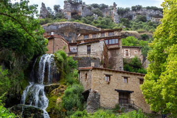 Fototapeta na wymiar Beautiful town crossed by a waterfall that flows into the nearby Ebro River. Orbaneja del Castillo, Burgos, Spain.