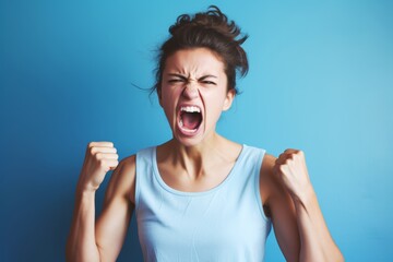17-year-old Caucasian woman, his face contorted in anger, fists clenched, expressing aggression due to a heated argument, set against a solid pastel blue copy space background.