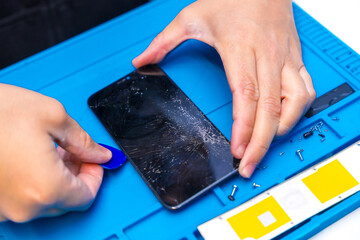 Technician using a pick to open a mobile phone