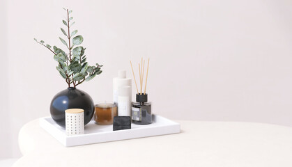 Mock up of essential oil, lotion bottle, reed stick diffuser in white tray on cream counter table with tree twig in black vase for cosmetic, skincare, beauty, body treatment product background 3D