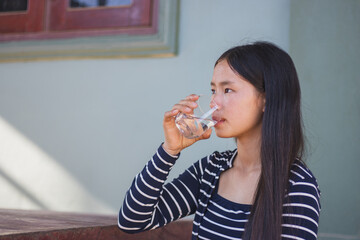 A women holding and drinking glass of water at home