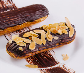 Chocolate eclairs with almonds on plate