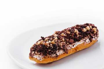 eclair with chocolate and nuts on a white plate