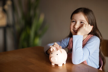 Obraz na płótnie Canvas happy child holding pig piggy bank. concept of saving money, investments, loans to families, deposits for education