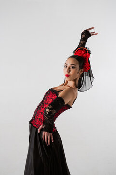 Woman dancer dancing on white background. Female in flamenco style dress performs elegant spanish dance moves with her hands and body in the studio.