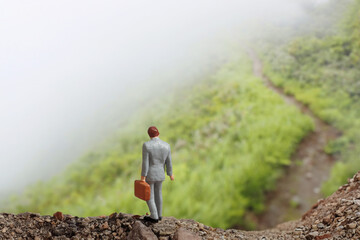 Naklejka premium 霧中の山道を歩く一人のビジネスマン
