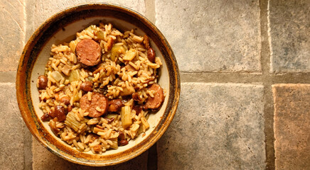 stoneware bowl of homemade Louisiana Cajun style red beans rice and sausage on a rustic porcelain...