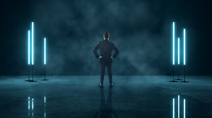 Businessman with hands on hips facing neon blue light panels in dark, foggy room. Futuristic...