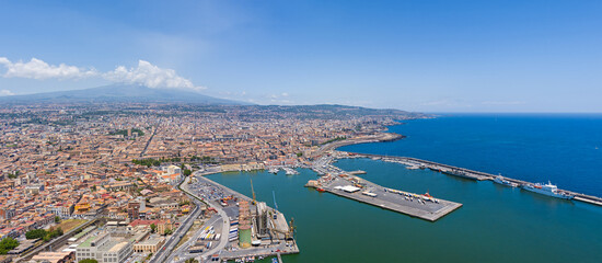 Catania, Sicily, Italy. City port with ships. Volcano Etna smokes in the clouds in the background....