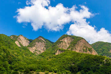 Mountains covered with green forest and blue sky with clouds