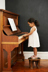 Piano, stool and kid in home for learning, practice and classical education with musical notes....