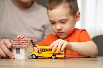 Dad and son play with a house and a school bus. Spending time with children. The concept of a happy...