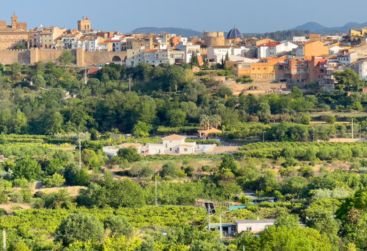 Rural landscape in Segorbe town. Farmhouse at vegetable field. Spain farmland. Cultivation of crops, production of food. House in farm field against backdrop of residential buildings in city