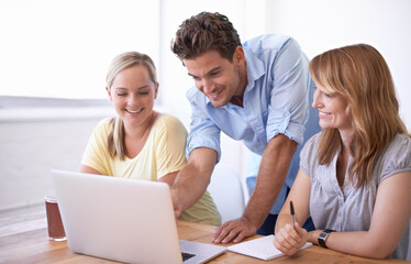 Group, desk and laptop for brainstorming, teamwork and collaboration in modern office in Canada. Employees, people or colleagues with smiles, table and paperwork for business or team meeting