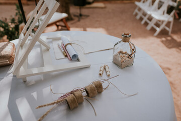 Detalles de decoración de una mesa al exterior, botella pequeña de cristal con arena.