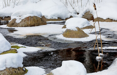 Snowy stones in small river in winter time