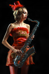 Woman in red dress with saxophone at the black background