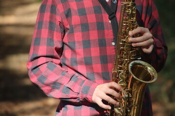A man's hand playing the saxophone in nature