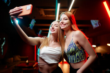 Two pretty young women taking selfie in the night club